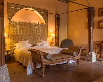 a bedroom with a large bed and a chair at Riad Noir d'Ivoire in Marrakech