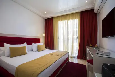 a hotel room with a bed and a television at Hôtel Racine in Marrakech