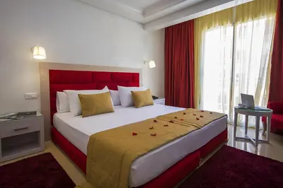 a bedroom with a large bed with a red headboard at Hôtel Racine in Marrakech