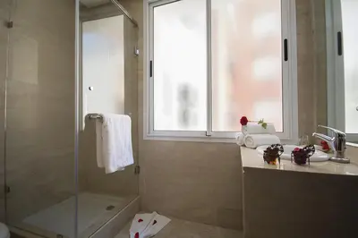 a bathroom with a shower and a sink and a window at Hôtel Racine in Marrakech