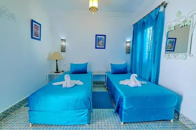 two beds in a room with blue walls at Riad Hôtel Essaouira in Marrakech