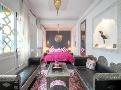 a living room with a pink bed and a couch at Riad Passali in Marrakech