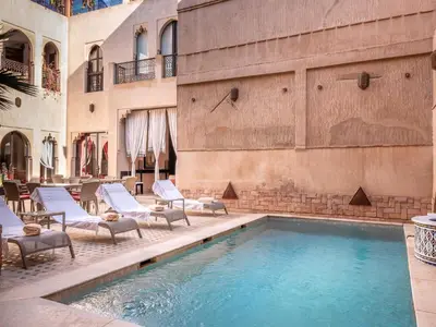 a swimming pool with lounge chairs next to a building at Riad Passali in Marrakech