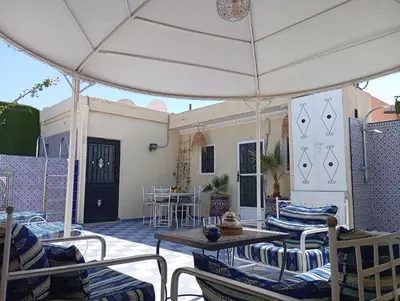 a patio with chairs and a table and an umbrella at Studio meublé proche du centre ville in Marrakech