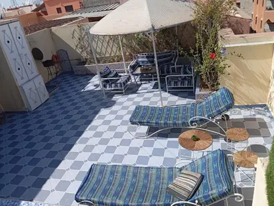 a patio with chairs and tables and an umbrella at Studio meublé proche du centre ville in Marrakech