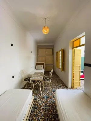 a room with two beds and a table in it at The Madrassa Hostel in Marrakech