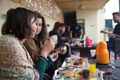 two women sitting at a table eating food at The Madrassa Hostel in Marrakech