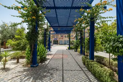 a blue pergola in a garden with trees at Wazo Hotel in Marrakech