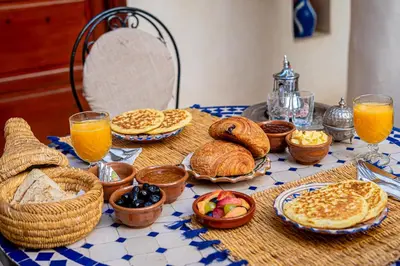 a table with bread and baskets of food and orange juice at Riad Chams Marrakech in Marrakech