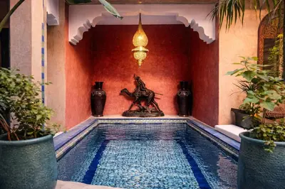a swimming pool in a house with a statue next to it at Riad Lapis-lazuli in Marrakech