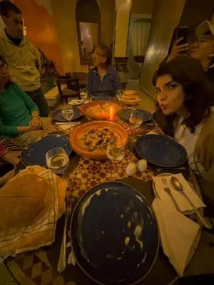 a group of people sitting around a table with pizza at Riad Lapis-lazuli in Marrakech