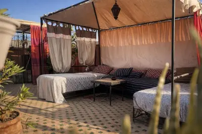 two beds in a tent with a couch and a table at Riad Lapis-lazuli in Marrakech