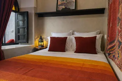 a bedroom with a bed with red and orange pillows at Riad Lapis-lazuli in Marrakech