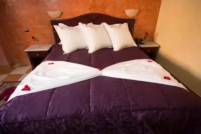 a bed with a purple comforter with red flowers on it at Appart Hotel Les Ambassadeurs in Marrakech