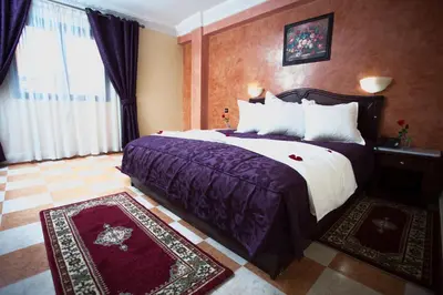 a hotel room with a large bed with purple sheets at Appart Hotel Les Ambassadeurs in Marrakech