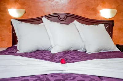 a bed with white pillows and a red toy on it at Appart Hotel Les Ambassadeurs in Marrakech
