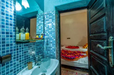 a blue tiled bathroom with a sink and a bed at Riad Haj Thami in Marrakech