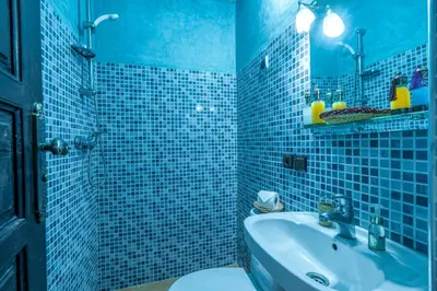 a blue tiled bathroom with a sink and a toilet at Riad Haj Thami in Marrakech