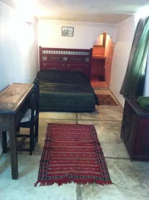a bedroom with a bed and a table and a rug at Riad Sabbah in Marrakech