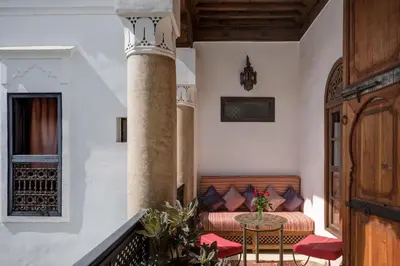 a balcony with a bed and a table and chairs at Riad Azzar in Marrakech
