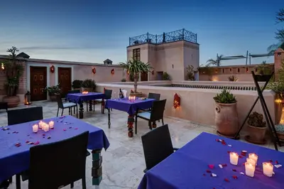a patio with blue tables and chairs and a building at Riad Siwan in Marrakech
