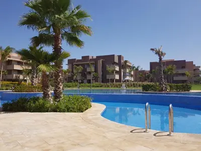 a swimming pool with palm trees and buildings at Prestigia 16 in Marrakech