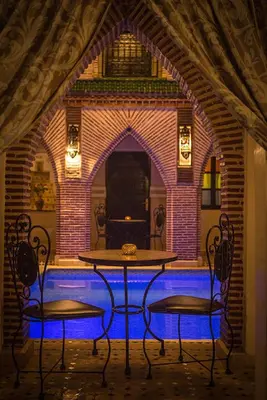 a table and two chairs in front of a brick wall at Riad Challa Hotel & Spa in Marrakech