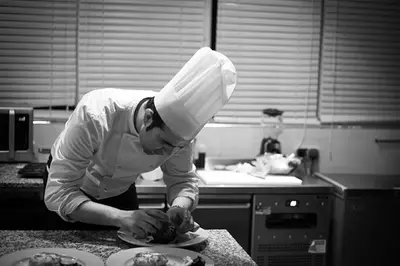 a man wearing a chefs hat preparing food in a kitchen at Riad Challa Hotel & Spa in Marrakech