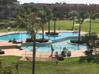 a large swimming pool with palm trees in a park at Prestigia Golf City Apartment in Marrakech