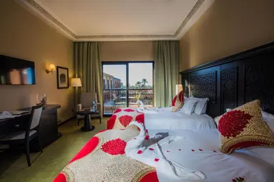 a hotel room with two beds and a window at Ennakhil Marrakech Hotel & SPA in Marrakech
