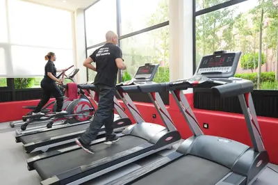 a man and a woman on a treadmill in a gym at Ennakhil Marrakech Hotel & SPA in Marrakech