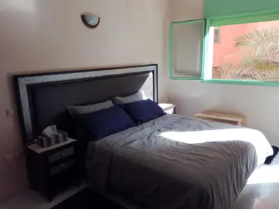 a bedroom with a bed with blue pillows and a window at Kim Apartment in Marrakech