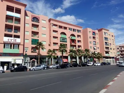 a pink building with cars parked in front of a street at Kim Apartment in Marrakech