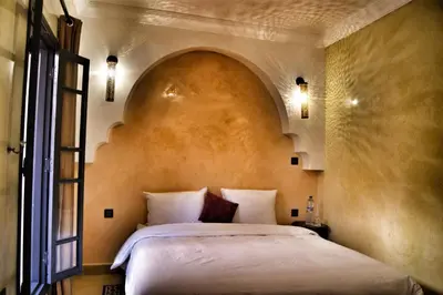 a bedroom with a large bed with an arch above it at Riad Abjaou in Marrakech