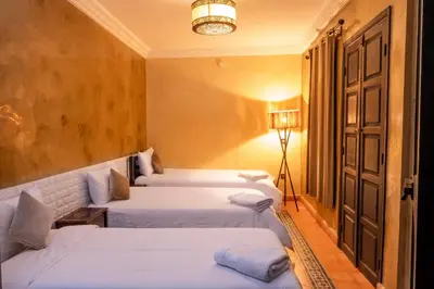 a hotel room with two beds and a lamp at Riad Abjaou in Marrakech