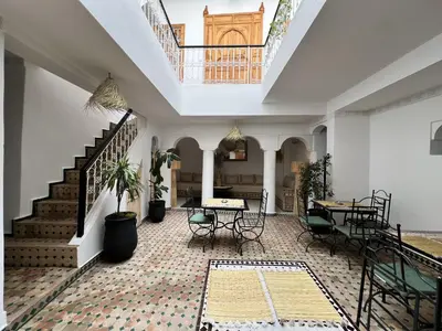 a room with a staircase and a table and chairs at Riad Sarah Sabrina in Marrakech