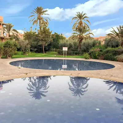 a swimming pool with a basketball hoop and palm trees at Comfortable Apartment in Marrakech with Shared Pool, 124 sqm in Marrakech