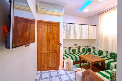 a living room with green chairs and a wooden door at Hotel Central Palace in Marrakech