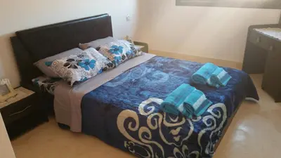 a bedroom with a bed with blue sheets and towels at Mouzdalifa Apartment In City Center in Marrakech