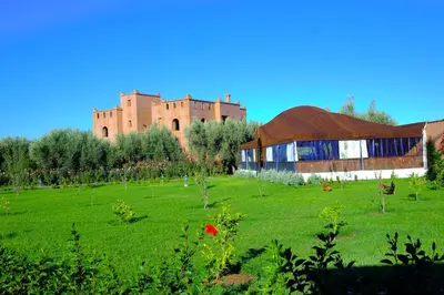 a green field with a building and a castle at Ferme Sidi Safou & Spa in Marrakech