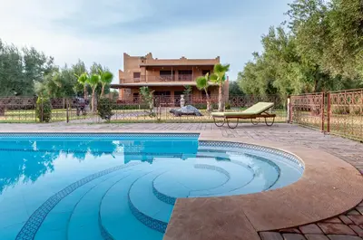 a swimming pool with a bench next to a house at Ferme Sidi Safou & Spa in Marrakech