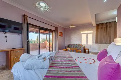 a bedroom with a large bed and a living room at Ferme Sidi Safou & Spa in Marrakech