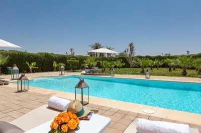 a swimming pool with a table with flowers on it at La Palmeraie De L'Atlas in Marrakech