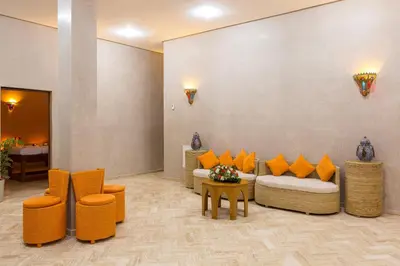 a lobby with couches and orange chairs and a table at La Palmeraie De L'Atlas in Marrakech