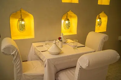a white table with white chairs and yellow lights at Riad Palais Blanc & Spa in Marrakech