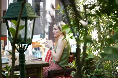 a woman sitting at a table with a glass at La Ferme Medina in Marrakech