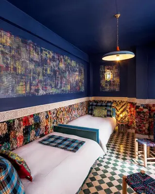 two beds in a room with blue walls and checkered floors at Riad Karmela Princesse in Marrakech