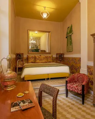 a bedroom with a bed and a table and a chair at Riad Karmela Princesse in Marrakech