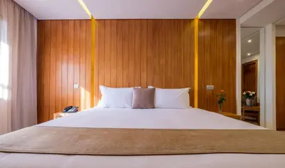 a bedroom with a large white bed with wooden walls at Hotel Ayoub & Spa in Marrakech