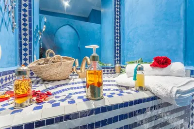 a blue tiled bathroom with a table with bottles of oil at Astra Damus Hotel in Marrakech